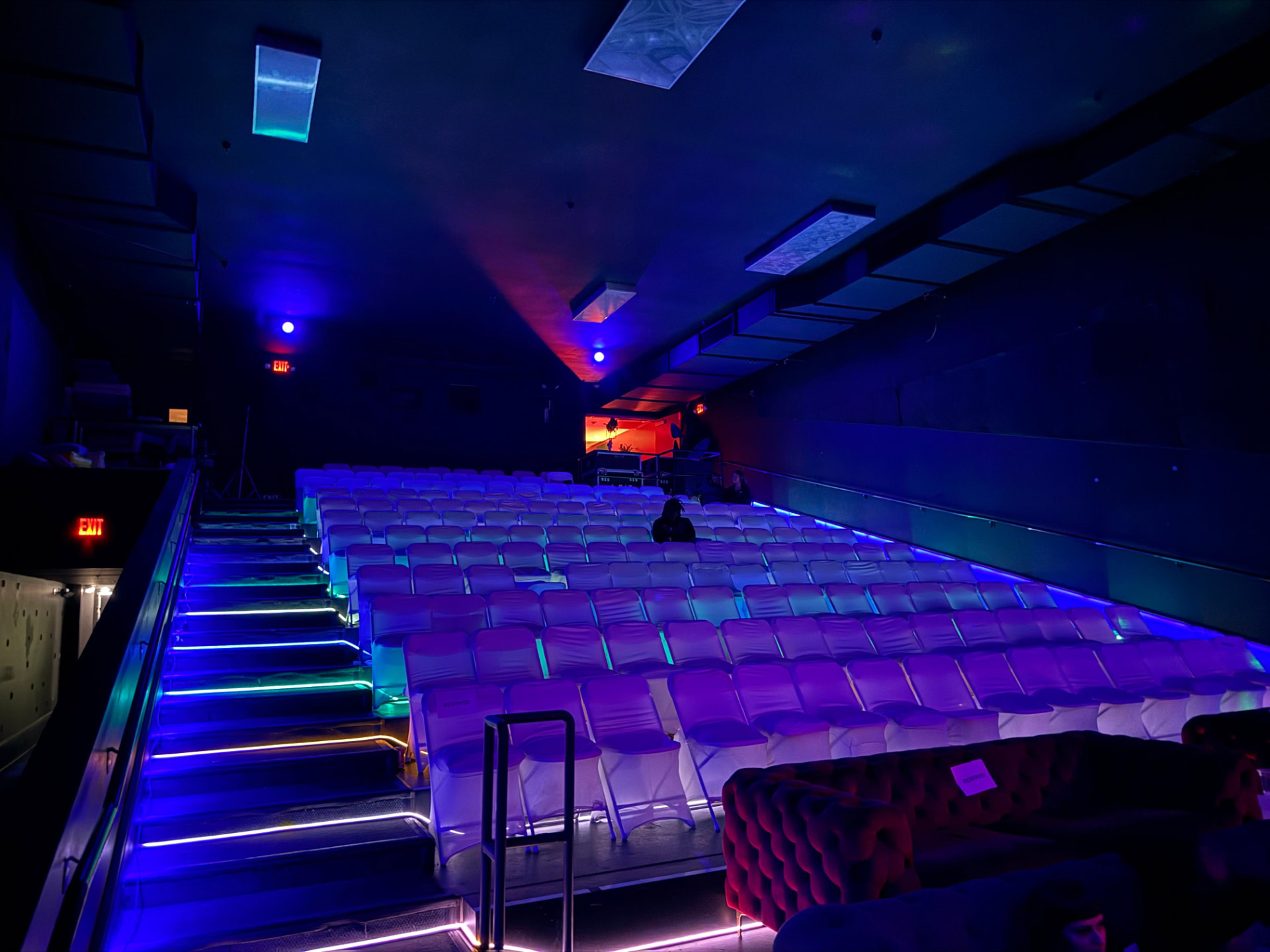 Rows of theater seats lit by blue and violet floor lighting