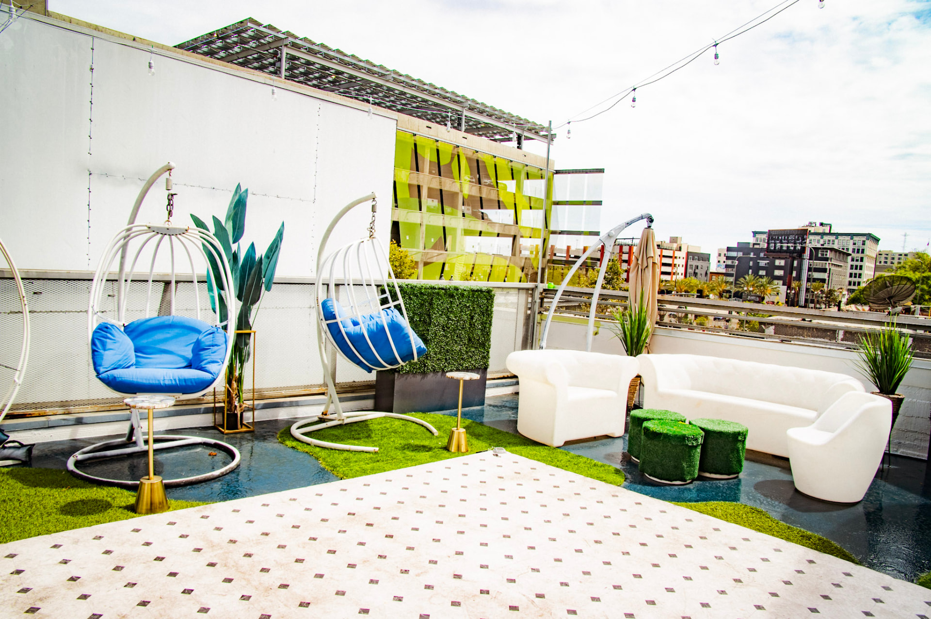 Rooftop swing chairs and white sofas on turf in afternoon light