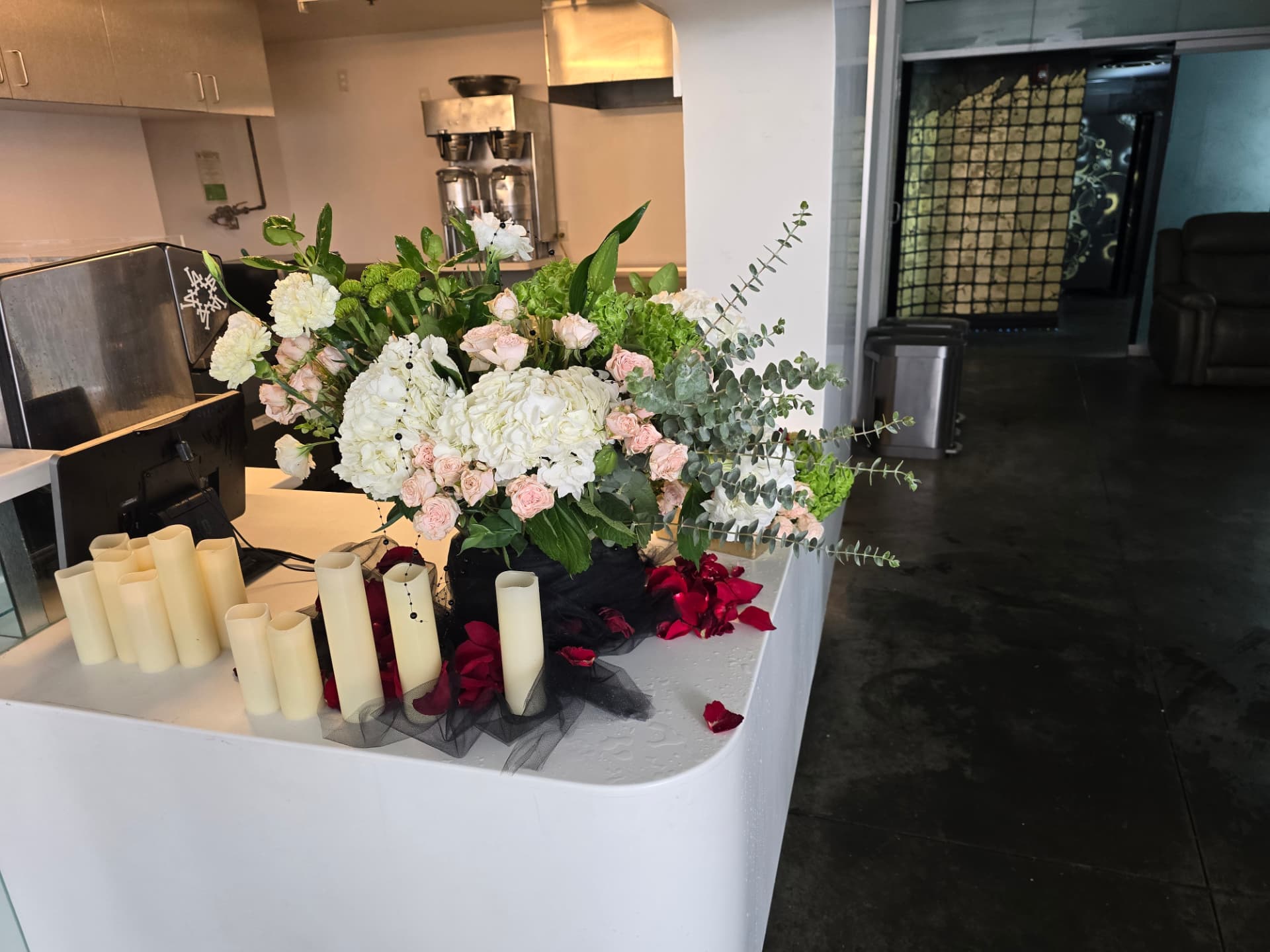 A white and blush floral centerpiece with candles on the lobby bar