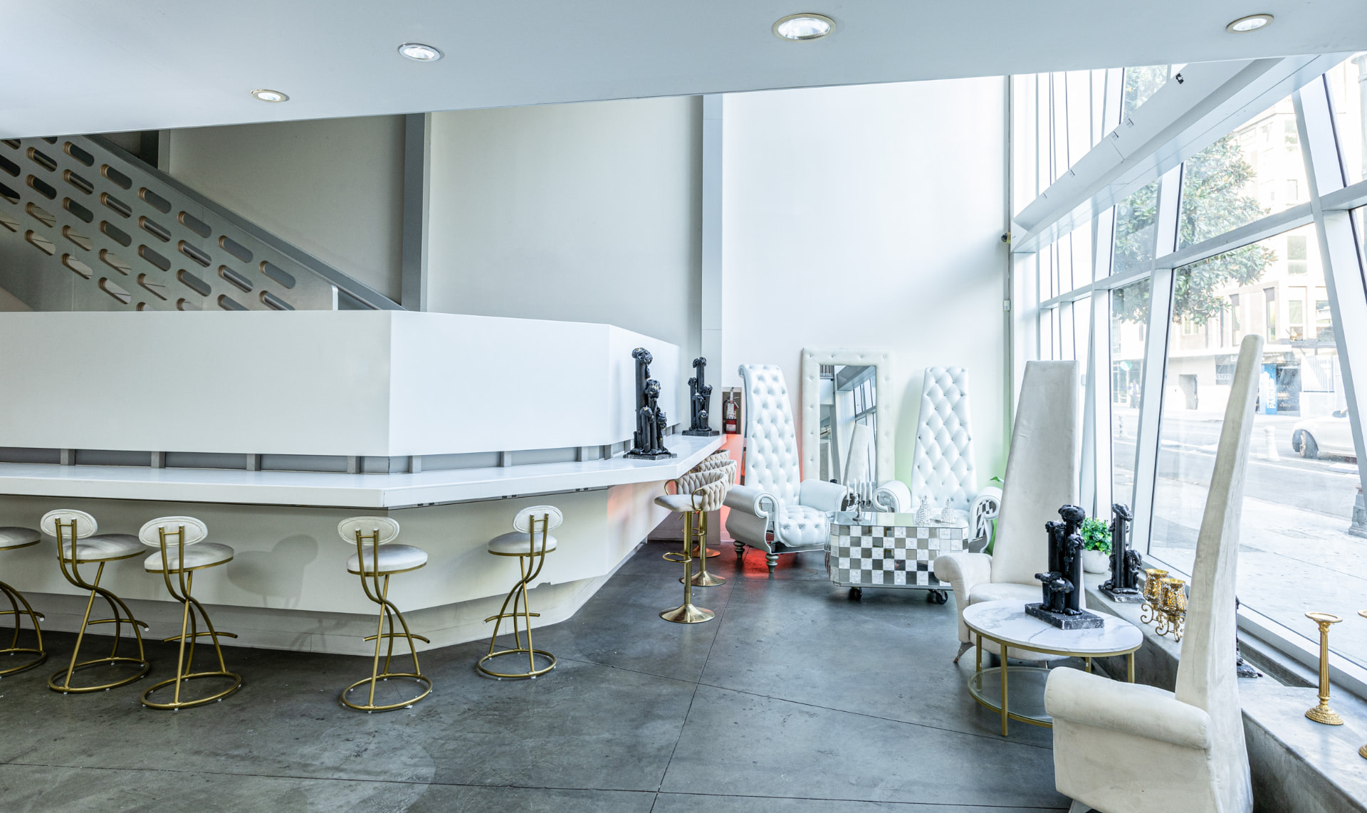 The sculptural lobby bar with brass stools beneath the atrium glass