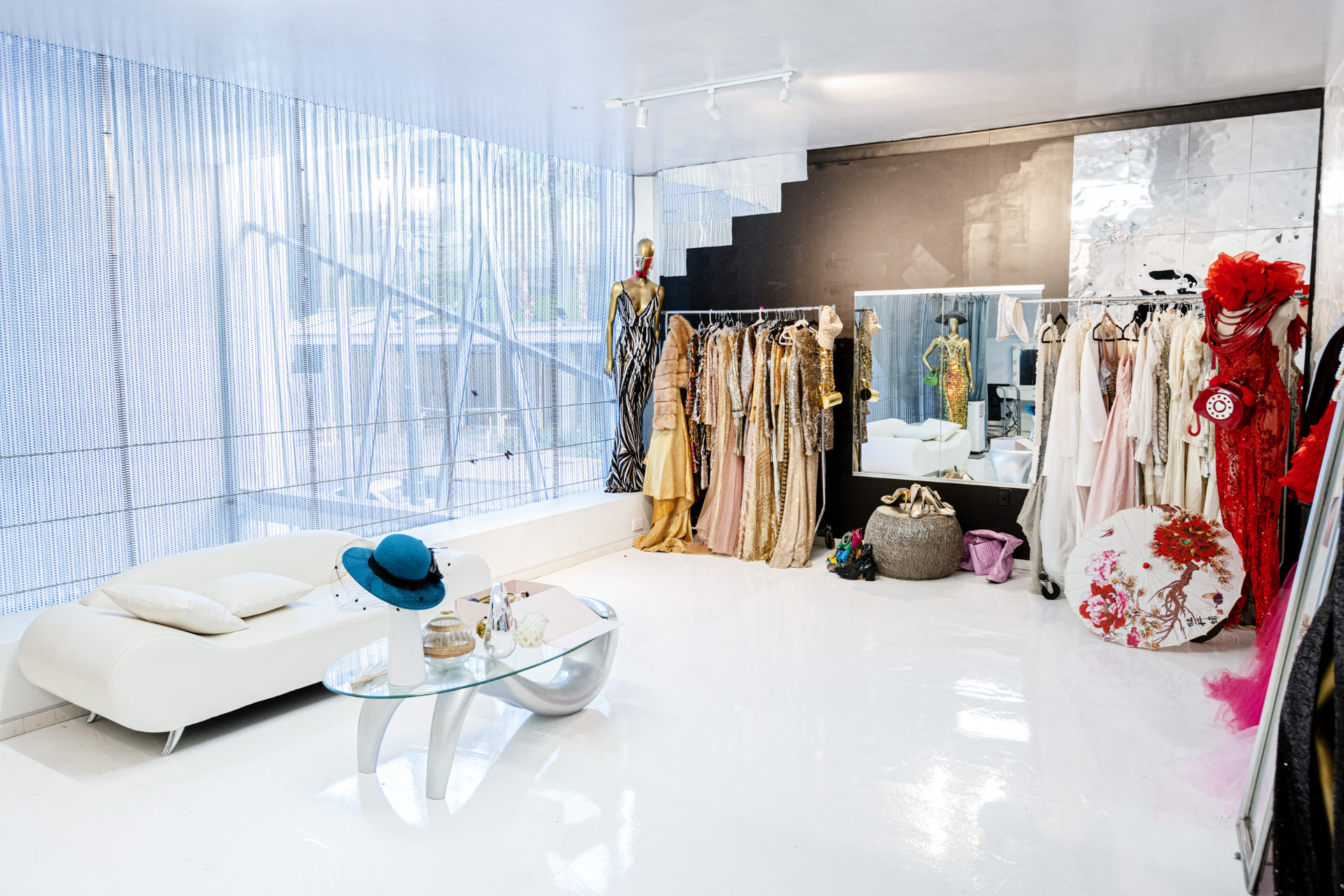 Gowns, a full-length mirror and a white chaise in the styling suite