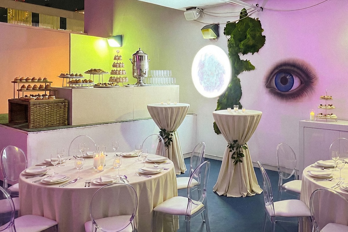 Rooftop dining and dessert display washed in pastel light beside the eye mural