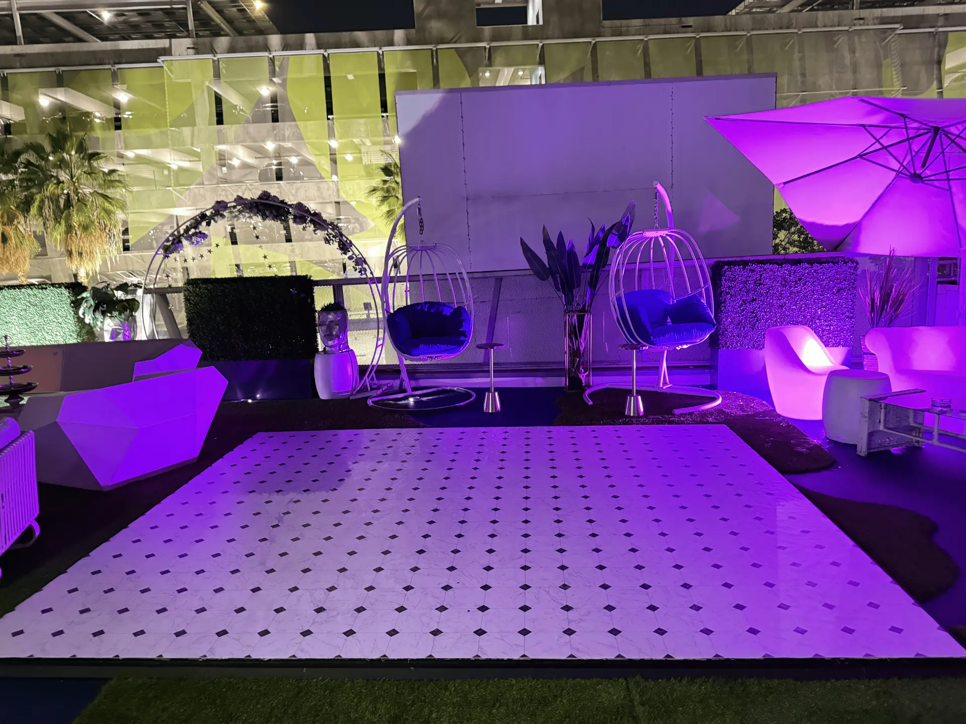 The rooftop dance floor at night with glowing furniture under purple light