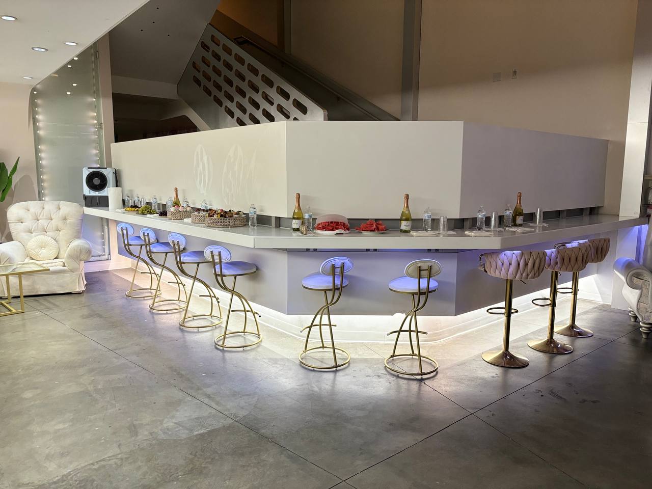 The lit lobby bar set with champagne, fruit and gold stools