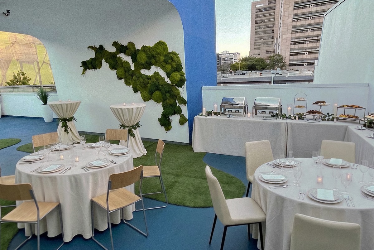 Rooftop dinner rounds and chafing buffet beside the moss wall