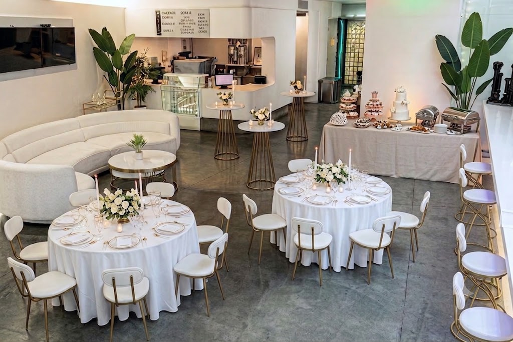 Lobby reception with gold-rimmed rounds, ivory florals and a tiered wedding cake