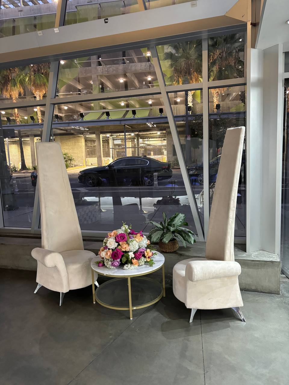 Tall ceremony chairs and a rose centerpiece in the glass atrium