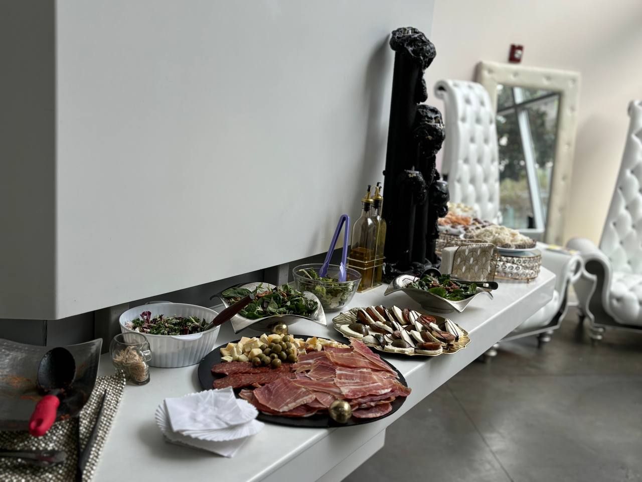 Charcuterie and salads on the lobby bar beside white throne chairs