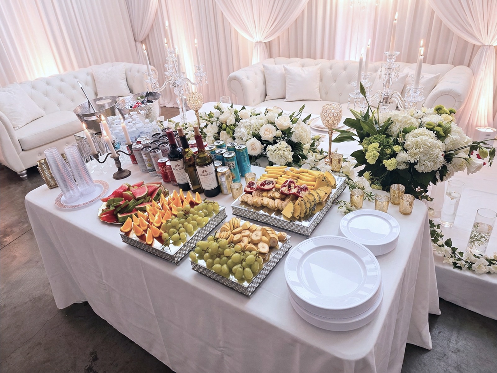 Draped reception buffet with white florals, candelabras and tufted sofas