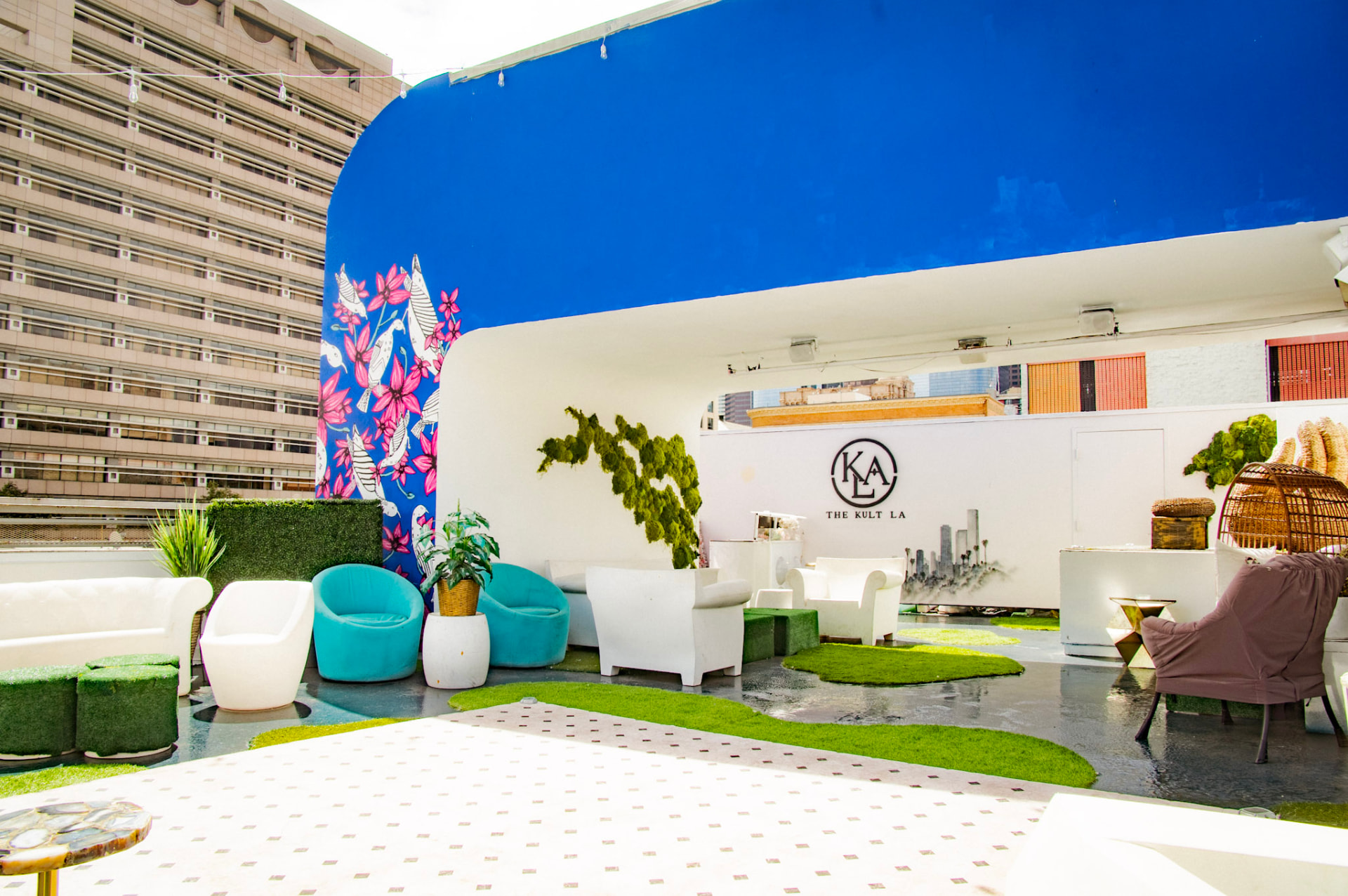 Rooftop lounge with the KLA monogram wall, floral mural and white seating