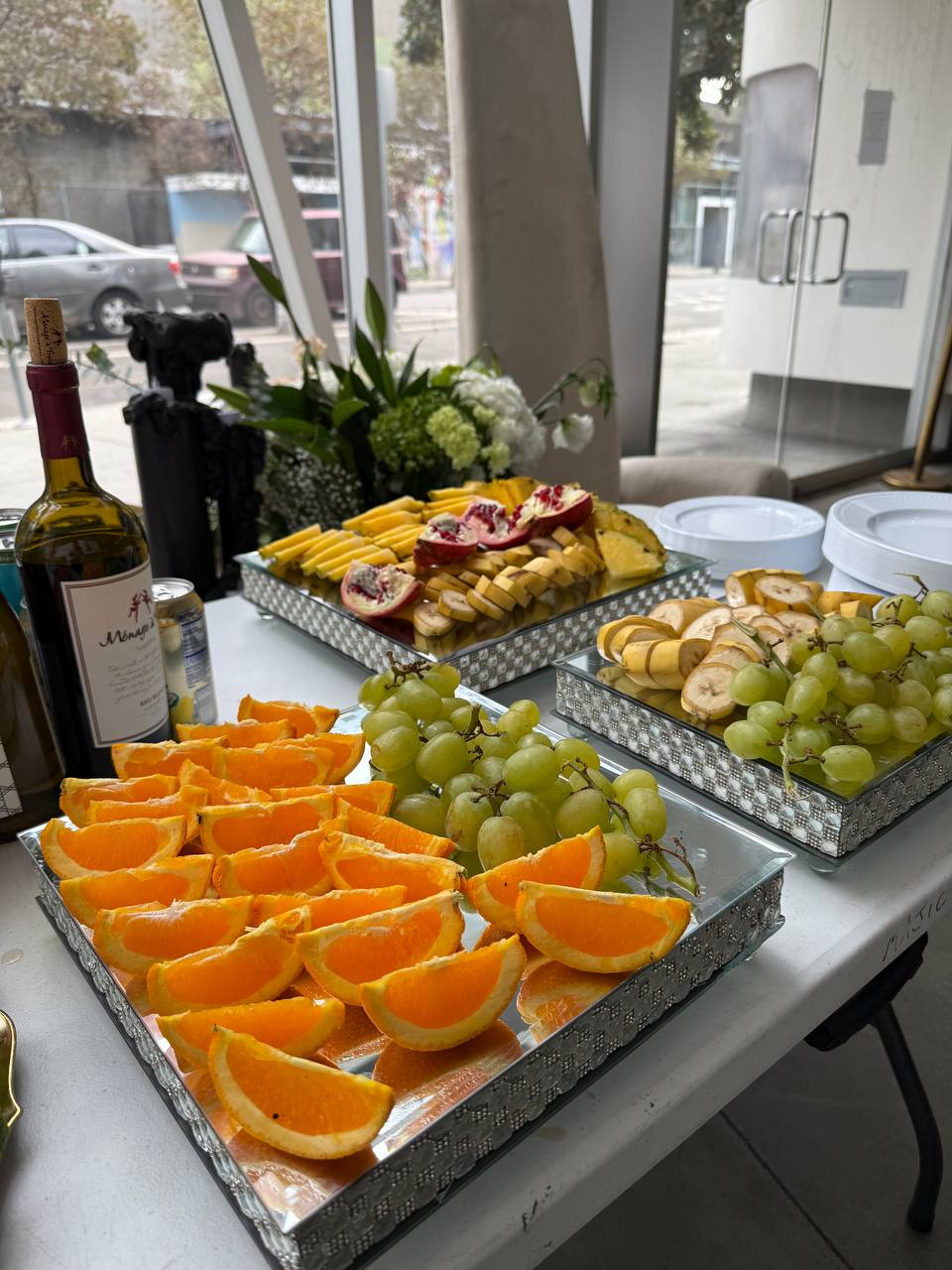 Fruit platters and wine on a mirrored table by the street-front windows