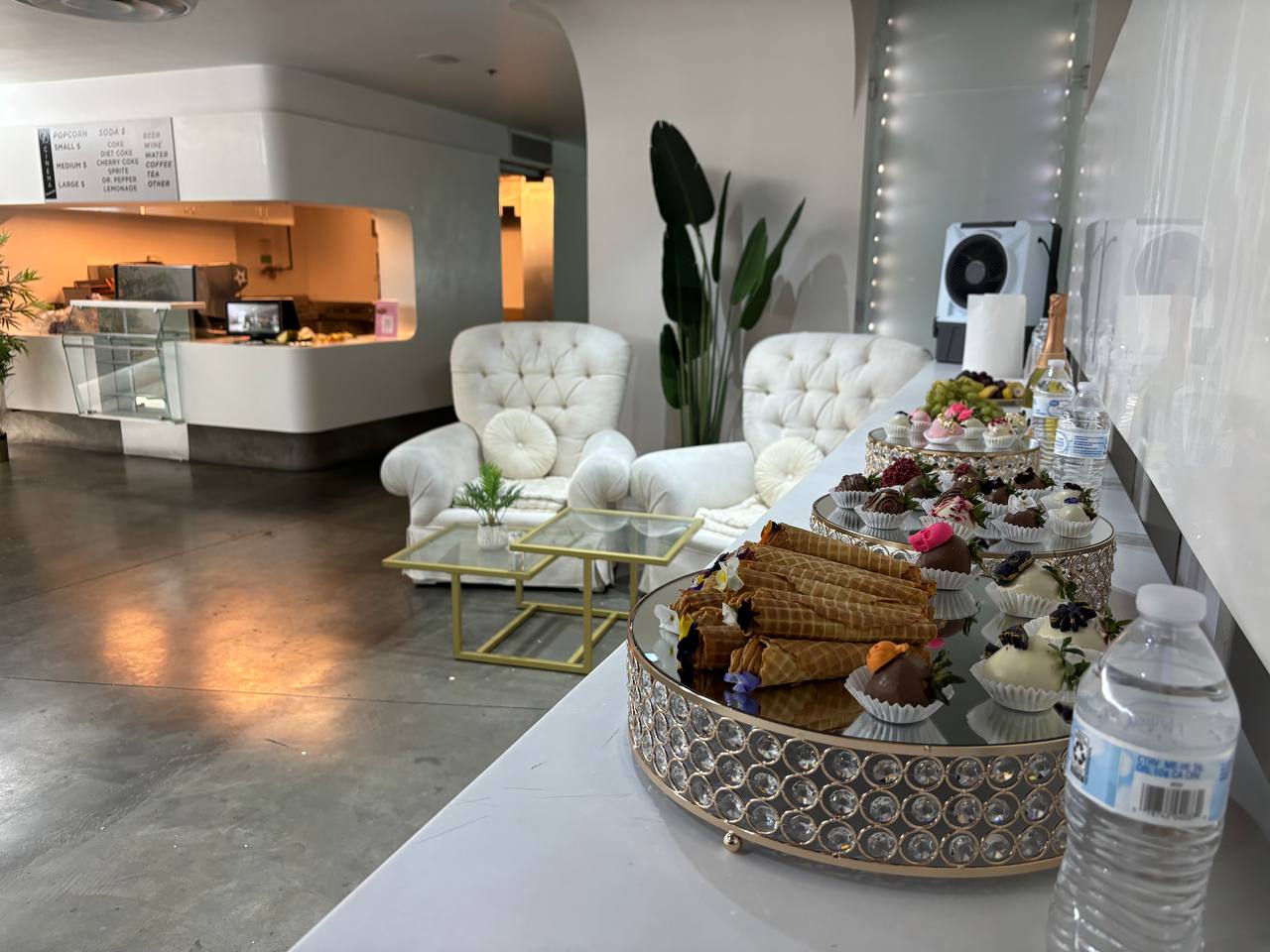 Tufted white armchairs beside a dessert-lined bar in the lobby